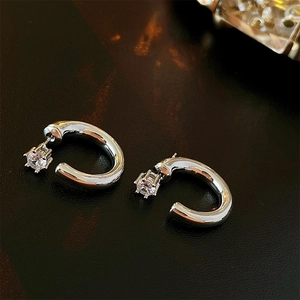 Close-up of silver C-shaped multi-layer metal earrings with clear zircon stones