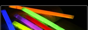 Vibrant glowing sticks in multiple colors illuminating open book pages in the dark