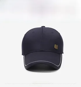 Detail of navy blue cotton twill baseball cap with silver reflective brim and gold plate