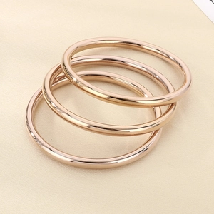 Detailed view of three stacked 18k rose gold-plated hollow bangles with mirror polish finish