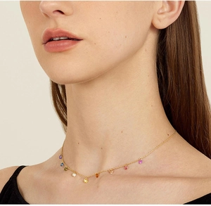 Detail of 18K gold plated necklace with colorful gemstones on a model neck