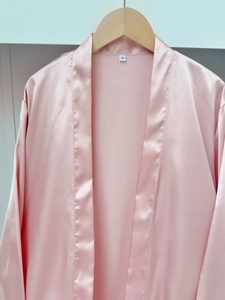 Detail of pink satin bathrobe with silky texture and S size label on wooden hanger