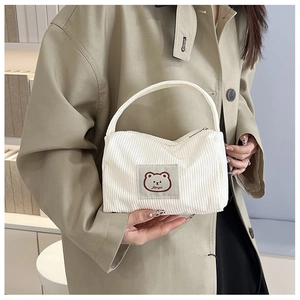 Detail of white corduroy mini handbag featuring a cartoon bear woven label and fanyu logo