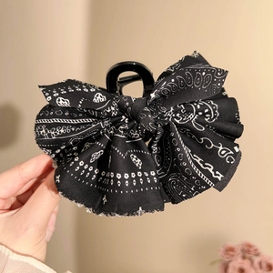 Dettaglio di un grande fermaglio per capelli con fiocco paisley nero per lo styling