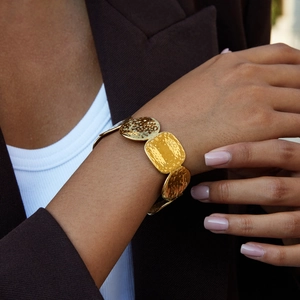 Detailed view of an 18K gold hammered texture cuff bracelet worn by a model