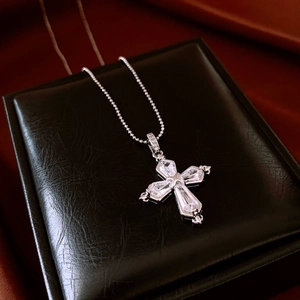 Close-up of zircon cross necklace featuring clear trapezoidal stones and silver bead chain