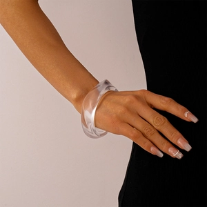 Close-up of a wide transparent acrylic bangle on a wrist with a minimalist design