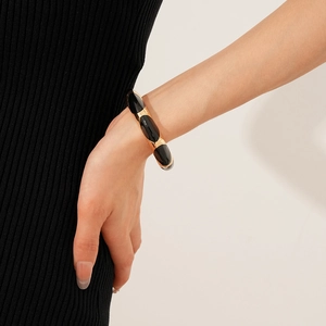 Detail of a vintage golden cuff bracelet with black oval enamel worn on a wrist