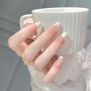 Elegant French press-on nails with nude pink base, white tips, pearls, and gold beads