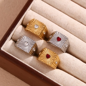 Detail of vintage heart rings with sunburst patterns and red or white gems in a box