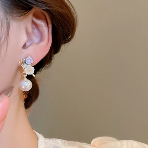 Gros plan de boucles d'oreilles perles avec fleurs en émail sur un mannequin