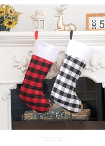 Close-up of red and white plaid Christmas stockings with plush trim on a festive fireplace