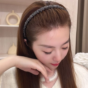 Close-up of a dark grey sparkling headband with teeth on a model in a cozy setting