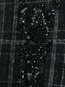 Macro detail of plaid knit fabric with handmade 3D floral beadwork and silver sequins