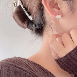 Detail of a minimalist 925 silver stud earring with a textured shell-inspired spiral design