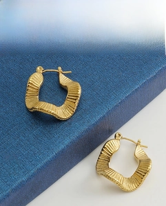 Detail showing the 18K gold-plated wavy textured hoop earrings with a clasp closure