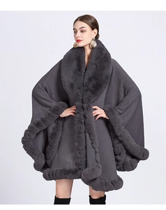 Detailed view of gray knit poncho featuring thick faux fur trim and elegant loose fit cut
