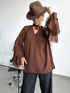 Detail of brown chiffon blouse featuring layered ruffle sleeves and a V-neck tie closure