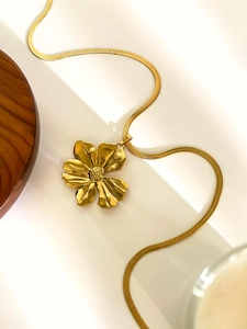 Macro shot of gold floral pendant featuring high-polish finish and flat snake bone chain