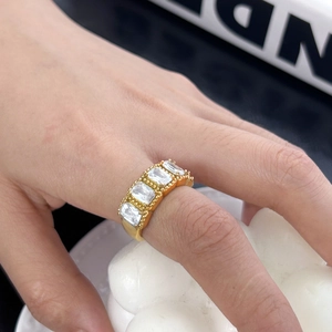 Detailed close-up of golden ring with four rectangular zircons and beaded edge details