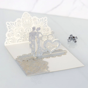 Detail of laser-cut wedding card with glitter accents and 3D bride and groom silhouette