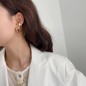 Detailed view of irregular liquid gold earrings and necklace on a model in white suit