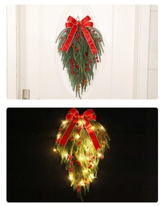 Detail of Christmas teardrop wreath with red berries, bow, and warm LED lights