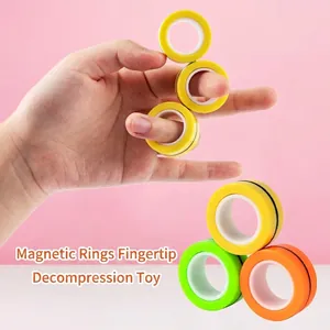 Colorful magnetic finger ring fidget toys for stress relief shown on hand with pink background