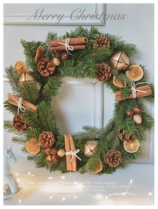 Close-up of Christmas wreath with pine needles, cinnamon sticks, orange slices and bells