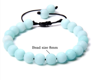 Detail view of 8mm natural light blue stone beads on an adjustable braided cord bracelet