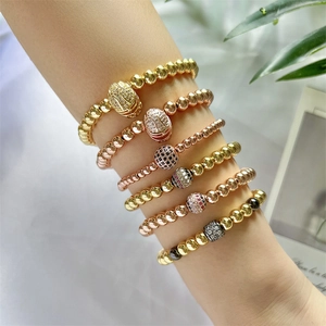 Close-up of stacked gold and rose gold beaded bracelets with zircon-studded accents