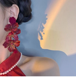 Detailed view of oversized burgundy fabric rose earrings worn in warm sunset lighting