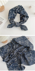 Detail view of navy blue paisley print scarf showing knotted style and fabric texture