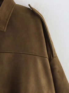 Detailed close-up of brown suede jacket shoulder tab and fine stitching texture