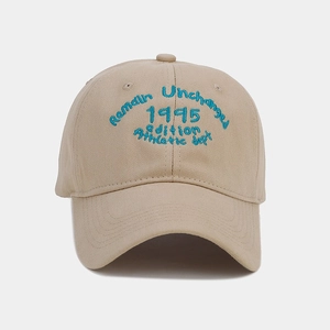 Detailed close-up of cotton baseball cap with blue 1995 embroidery on beige twill fabric