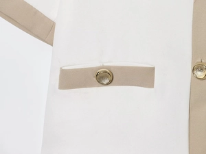 Detailed close-up of pocket stitching and gold metal buttons on a two-tone blazer
