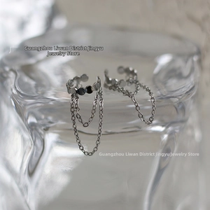 Detail of silver metal ear cuffs with double layer chain tassels on a glass edge
