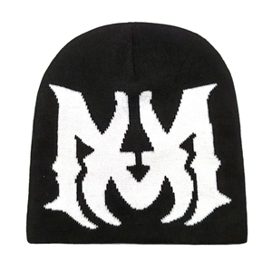 Close-up of a black knit beanie featuring a large white gothic letter M jacquard pattern