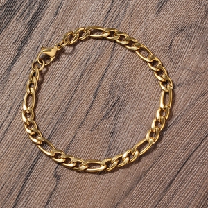 Detail of 5mm gold plated stainless steel Figaro chain bracelet on a dark wood background