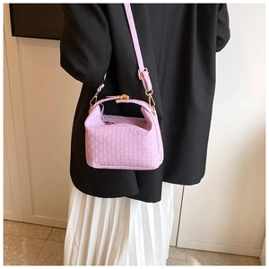 Detail of light purple woven texture handbag with gold hardware worn with a black blazer