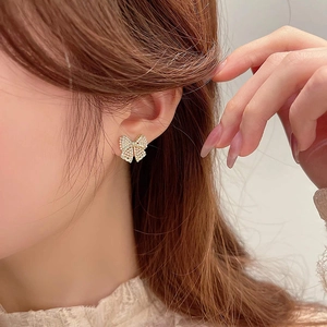 Detailed side view of elegant bow earrings with pearls and gold-tone metal base