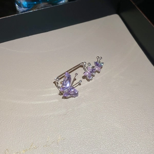 Macro shot of silver ear cuff with three sparkling purple zircon butterflies on soft leather