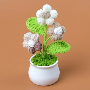 Detalle de flores de ganchillo hechas a mano con pétalos blancos y marrones en maceta blanca