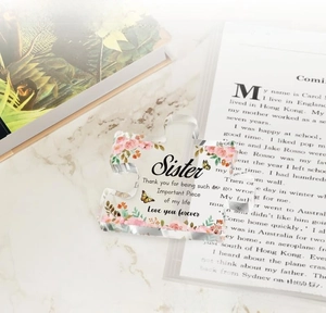 Detail of puzzle-shaped acrylic paperweight with floral pattern and sister quote