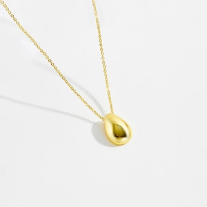 Polished gold teardrop pendant necklace with a delicate chain on white background