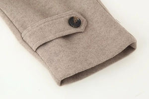Detail view of khaki wool jacket sleeve with amber textured button and strap