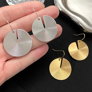 Macro detail of round spiral earrings in silver and gold minimalist metallic finish