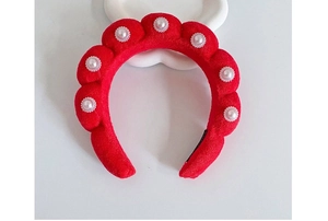 Detailed shot of a red velvet twisted headband with elegant white faux pearl embellishments