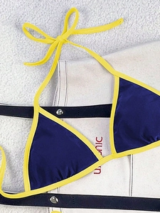 Flat lay of navy blue bikini top with yellow contrast trim and halter neck ties