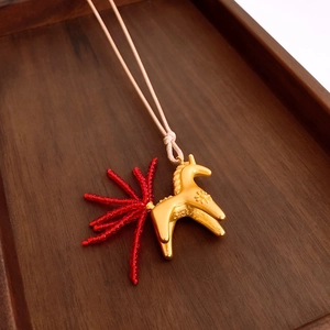 Macro detail of horse pendant with sun pattern and unique red beaded glass tail